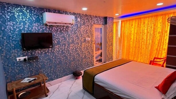 A modern bedroom with a bed, a TV, an air conditioner, and a window with curtains. - Hotel Palace- Near Ruby Hospital (Kolkata)