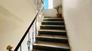 A staircase with black railings and a potted plant at the top. - Hotel Palace- Near Ruby Hospital (Kolkata)