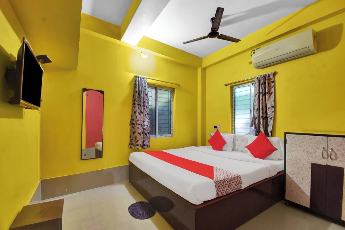 A hotel room with a bed, a wardrobe, a ceiling fan, an air conditioner, and a window with curtains.