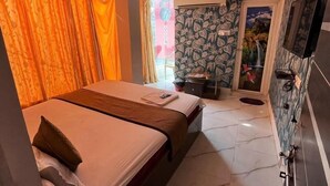 A hotel room with a bed, a small desk, a mirror, and a TV. - Hotel Palace- Near Ruby Hospital (Kolkata)