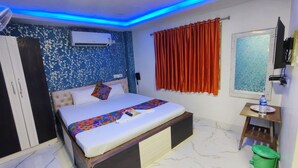 A bedroom with a bed, a wardrobe, a small table with a water bottle, and a window with curtains. - Hotel Palace- Near Ruby Hospital (Kolkata)