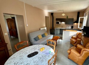 A compact living space with a sofa, a dining table, a kitchen area, and a television. - Le Flocon Le Mont Dore 4 pers (Mont-Dore)