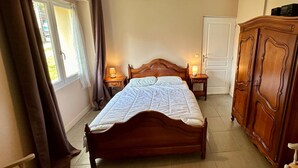 Een slaapkamer met een houten bed, twee bedlampen, een kledingkast en een raam met gordijnen.