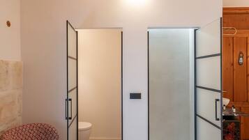 Un dormitorio con una cama, una silla, un armario y un baño con inodoro.