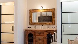 Una cocina moderna con un mueble de madera, un espejo y una mesa de vidrio con una bandeja.