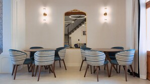 Comedor con una mesa grande y seis sillas, un espejo y dos lámparas de pared.