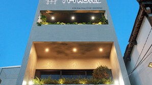 A modern hotel with a flat facade, a rooftop garden, and illuminated signage.
