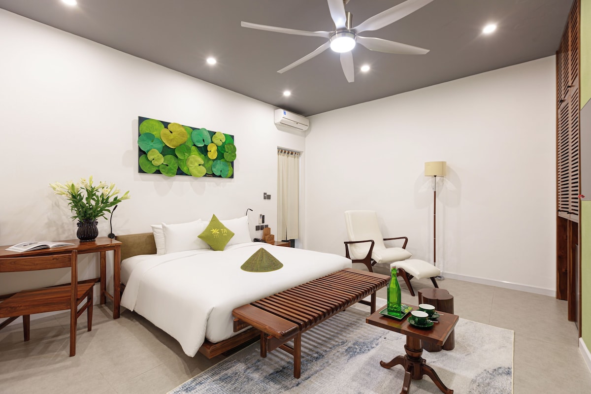 Una habitación de hotel moderna con cama, mesita de noche, lámpara y ventilador de techo.