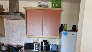 A compact kitchen with pink cabinets, a microwave, a toaster, a coffee maker, and a refrigerator. - Quaint 2-bedroom apartment with WiFi in charming Wolverhampton city centre (Wolverhampton)
