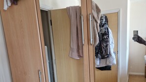 A wooden wardrobe with multiple compartments and a mirror. - Quaint 2-bedroom apartment with WiFi in charming Wolverhampton city centre (Wolverhampton)