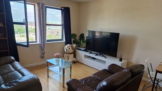 A living room with a sofa, a glass coffee table, a TV on a stand, and a window with curtains. - Quaint 2-bedroom apartment with WiFi in charming Wolverhampton city centre (Wolverhampton)