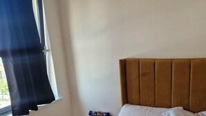 A bedroom with a bed, a nightstand, a window with curtains, and a headboard. - Quaint 2-bedroom apartment with WiFi in charming Wolverhampton city centre (Wolverhampton)