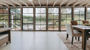Ein geräumiges Zimmer mit großen Fenstern, Holzboden und einer Essecke mit Stühlen und Tisch.