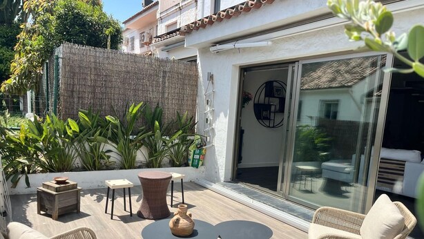Une terrasse avec des meubles en osier, une petite table et une plante en pot.