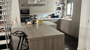 Une cuisine moderne dotée d’un îlot central, d’appareils électroménagers intégrés et d’une fenêtre donnant sur la pièce.