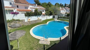 Une piscine entourée d’une pelouse bien entretenue, avec des maisons blanches en arrière-plan.