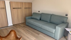 Un salon moderne avec un canapé gris, un fauteuil en osier et un plancher en bois.