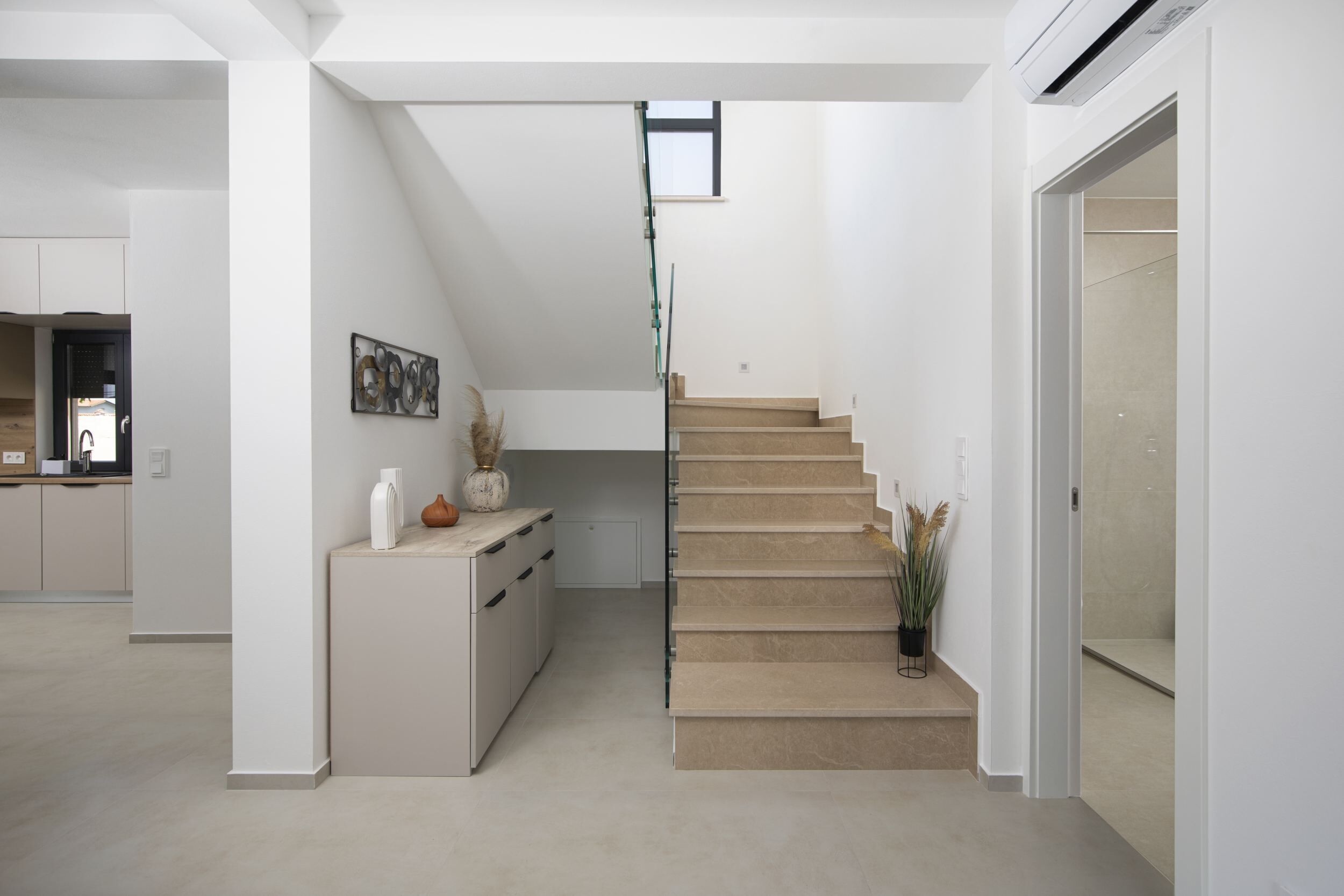 Et moderne interiør med en trappe til en etage ovenover, en receptionsdisk og et minimalistisk design.