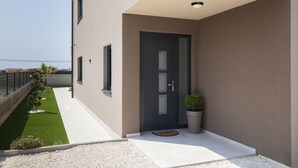 A modern building with a flat roof, a dark-colored door, and a small garden area with a pathway leading to the entrance. - Villa del Sol near Fažana (Valbandon)