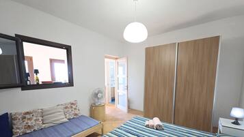 A bedroom with a bed, a sofa, a wardrobe, and a mirror.