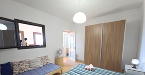 A bedroom with a bed, a sofa, a wardrobe, and a mirror.