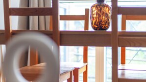 Une table à manger en bois, avec des chaises, un vase et une fenêtre avec des rideaux.