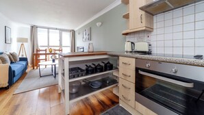 Une cuisine moderne dotée d’un four encastré, de meubles en bois et d’un coin repas avec une table et des chaises.