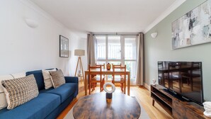 Un salon moderne avec un canapé bleu, une table à manger en bois et un téléviseur à écran plat.