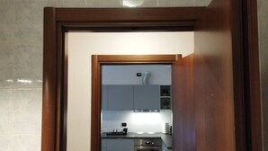 A modern kitchen with grey cabinets, stainless steel appliances, and a wooden-framed doorway. - Liguria 51 - RENT'CA (Milano)