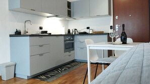 A compact kitchen with grey cabinets, a white countertop, and a dining area with a table and chairs. - Liguria 51 - RENT'CA (Milano)