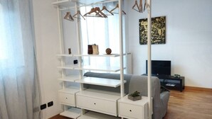 A bedroom with a white wardrobe, a bed, a TV, and a painting on the wall. - Liguria 51 - RENT'CA (Milano)