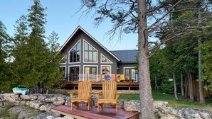A cabin with a deck, surrounded by rocks and trees.