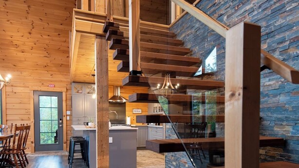 A modern interior with a wooden staircase, a kitchen area, and a dining space.