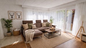Una sala de estar moderna con un sofá modular, una mesa de centro y ventanas amplias.