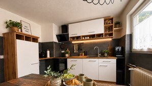 Una cocina moderna con armarios de madera, horno empotrado y comedor con mesa de madera dispuesta con comida y bebidas.