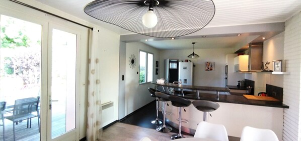 A modern kitchen with a bar area, a refrigerator, and a dining table with chairs.