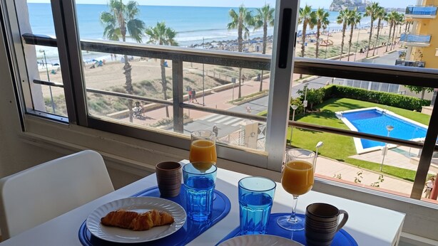 A breakfast table with croissants and orange juice, overlooking a beach and pool. - Front line, sea view, wifi, parking (Unknown)