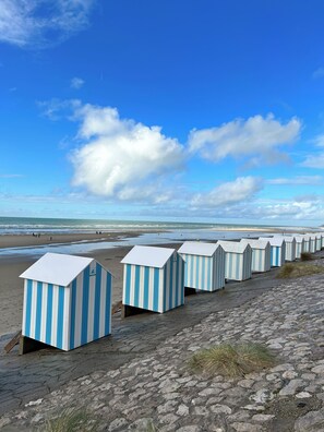 A row of beach huts with a clear view of the beach and ocean in the background.
