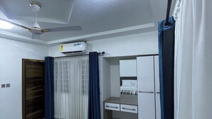 A bedroom with a bed, a desk, a wardrobe, an air conditioning unit, and a ceiling fan. - Villa Fafa — Comfort in style (Ho)