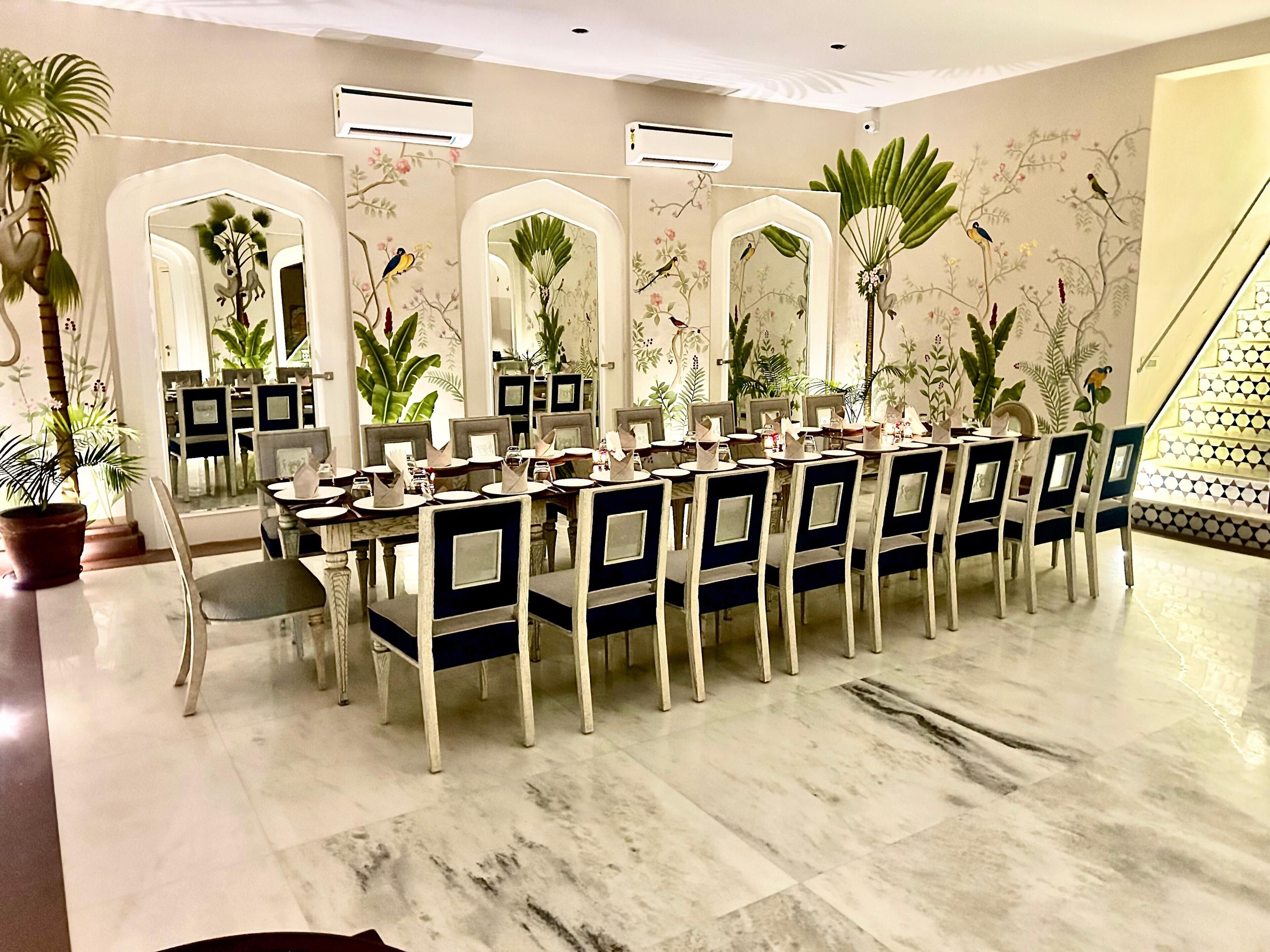 Un comedor formal con una larga mesa dispuesta para varios invitados, rodeada de sillas con respaldos decorativos.