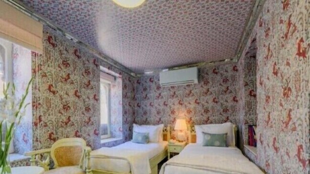 Ein Zimmer mit zwei Betten, einem Sessel, einem Tisch und einem Fenster.