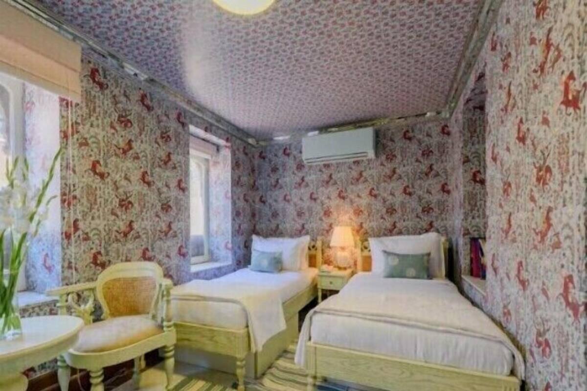 A room with two beds, a chair, a table, and a window.