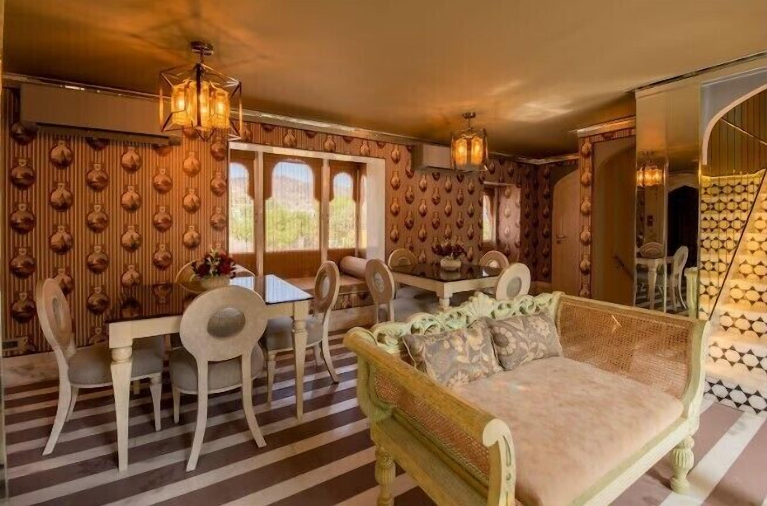 A dining area with a table and chairs, a sofa, and a patterned wall.