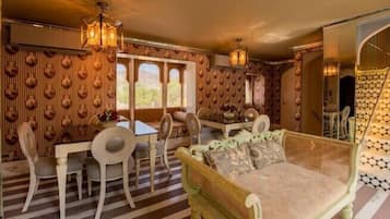 A dining area with a table and chairs, a sofa, and a patterned wall.
