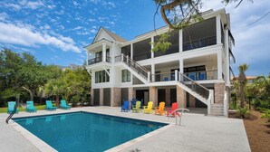 A two-story building with a pool, outdoor seating, and a staircase leading to the upper level. - Beautiful 9-Bedroom Coastal Retreat Second-Row, Ocean Views with Private Pool! (Georgetown)