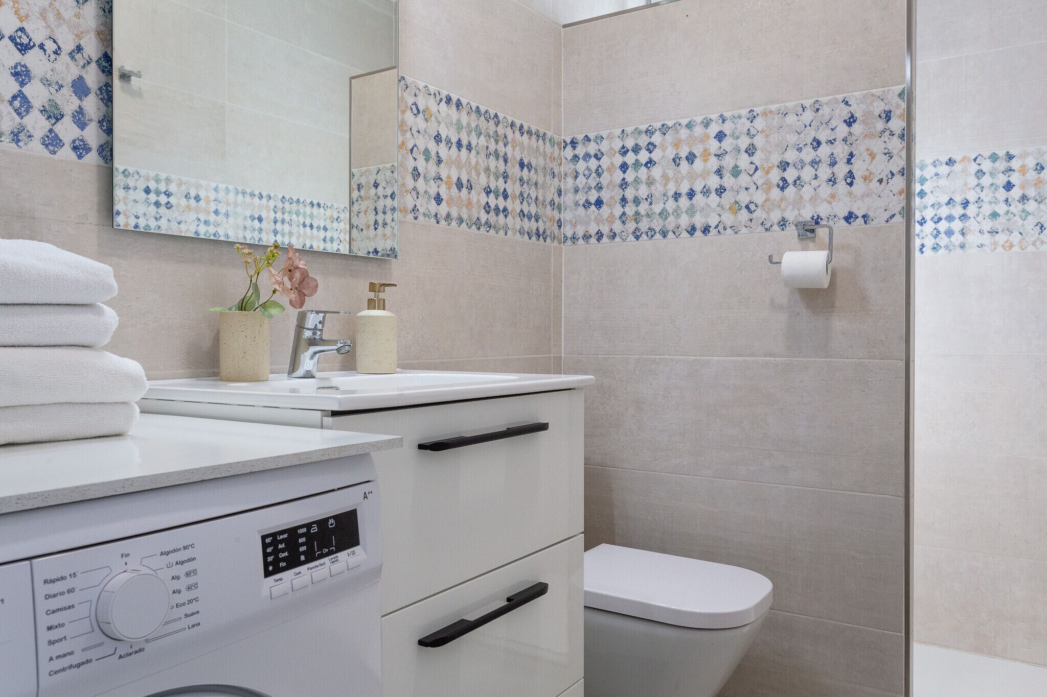 Ein modernes Badezimmer mit Toilette, Waschbecken und Spiegel.