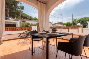 Une terrasse extérieure avec une table dressée pour deux personnes, entourée de chaises, et une vue sur le quartier.