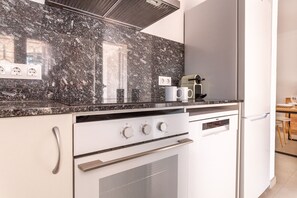 A modern kitchen with a granite countertop, built-in oven, and a coffee maker.