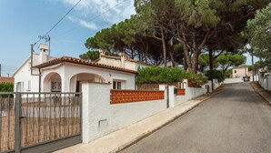 Une rue résidentielle bordée de maisons, avec une entrée sécurisée et des arbres.
