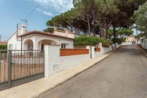 A residential street with houses, a gated entrance, and trees. - Casa Iris only 700 meters away from the beach (L'Escala)
